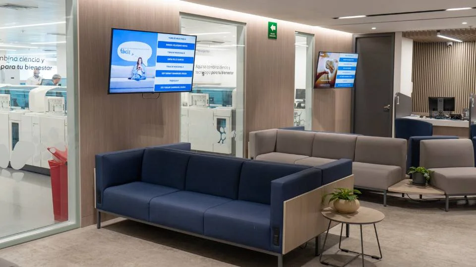 Moderna sala de espera corporativa con silletería ergonómica y monitores del sistema Qanty para el seguimiento del flujo