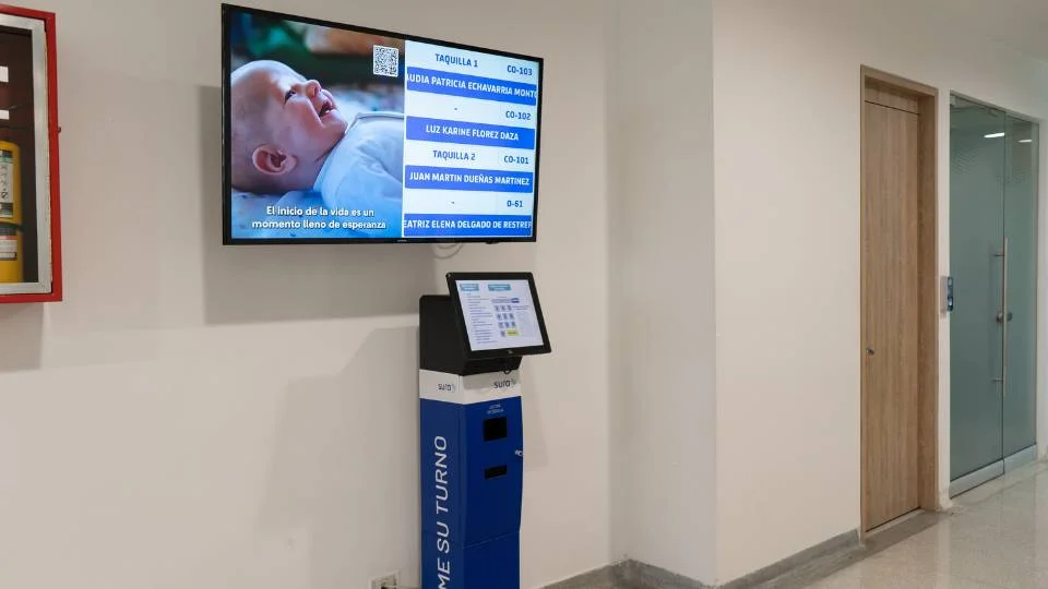 Punto integral de atención al cliente demostrando la sinergia entre el dispensador interactivo de piso y el monitor colgante